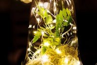 a cloche with some hay, greenery and lights is a lovely idea for an enchanted forest wedding