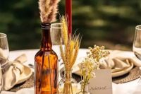 a cluster rustic fall wedding centerpiece of dried grasses and blooms and some candles is an easy to realize idea