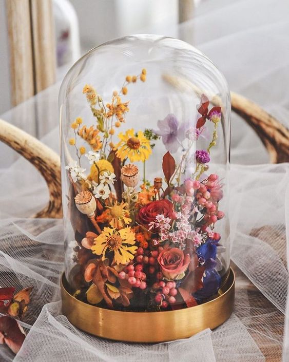 a colorful dried flower wedding centerpiece with pink, red, purple and yellow blooms and seed pods