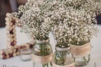 a combo of three mason jars wrapped with burlap and with baby’s breath is a cool idea for a rustic wedding