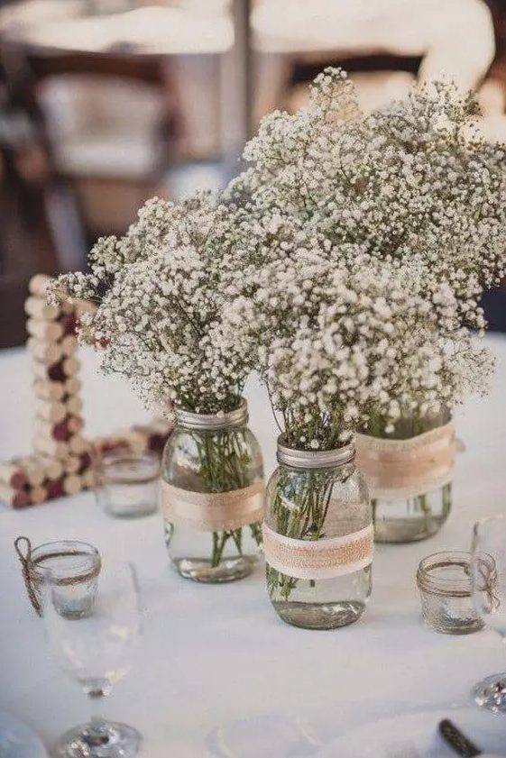 a combo of three mason jars wrapped with burlap and with baby's breath is a cool idea for a rustic wedding