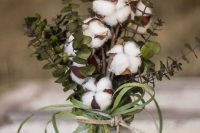 a cool fall or winter wedding centerpiece with eucalyptus, cotton and grass in a mason jar for a cozy relaxed wedding