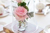 a couple of books plus pink roses in vases in a cloche look very romantic and beautiful