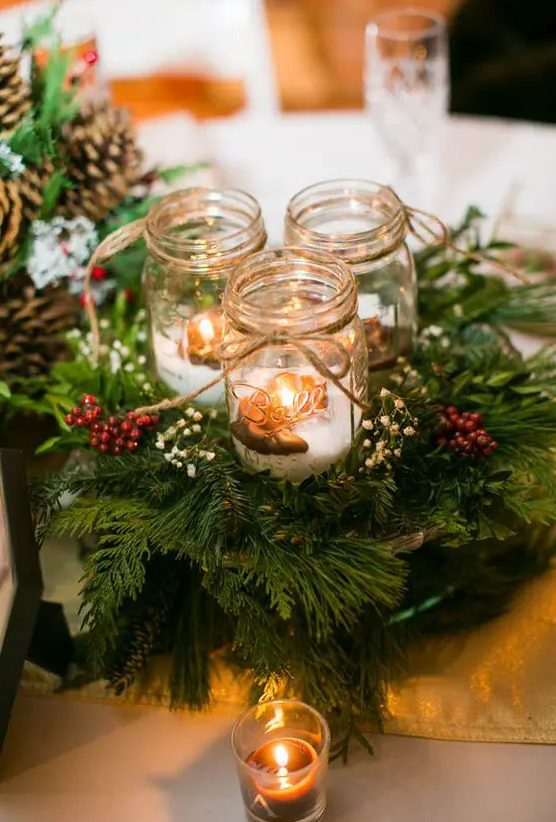 a cozy Christmas centerpiece of evergreens, berries, candle lanterns with fake snow