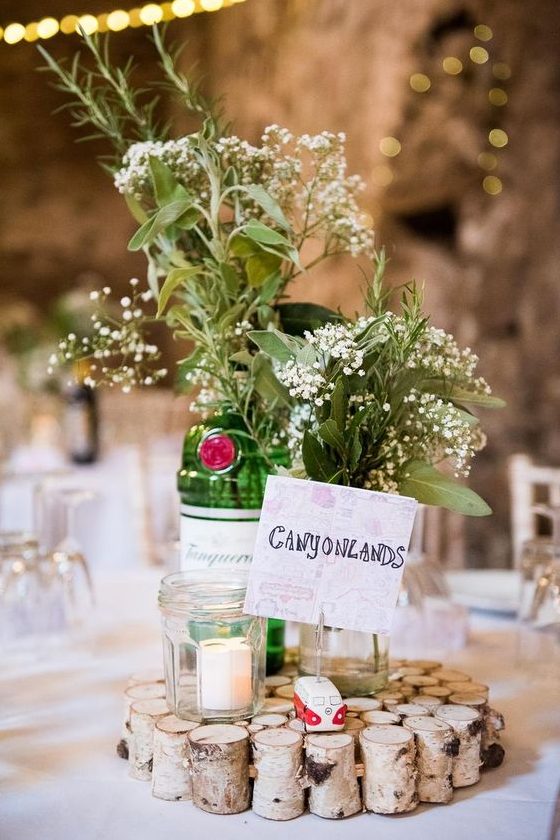 a cozy barn wedding centerpiece of sticks, candles, neutral blooms and greenery and a table name is great