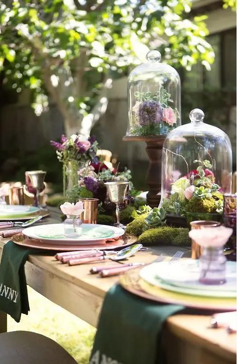 a fab enchanted forest wedding centerpiece of moss, greenery and dark and pink blooms and succulents is amazing and can be DIYed