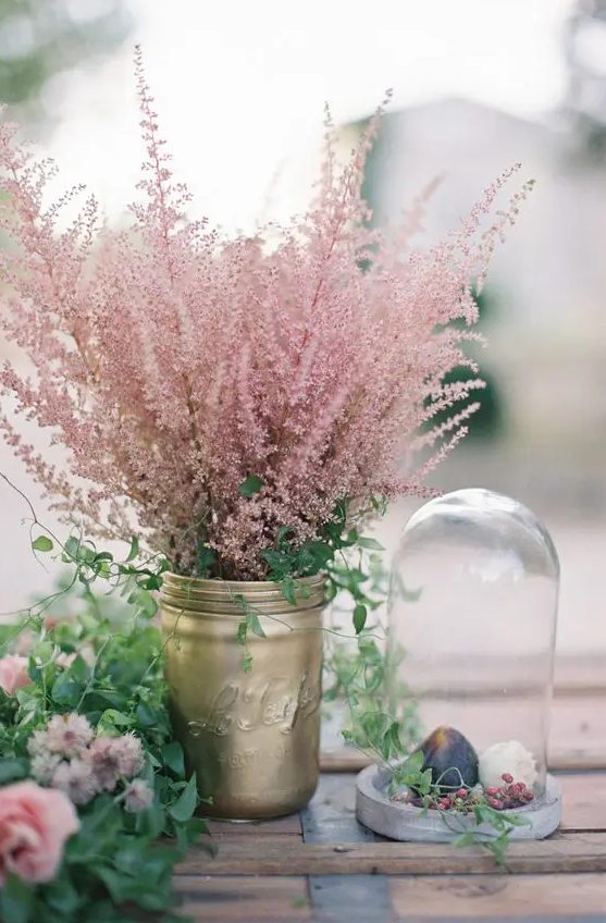 a gold mason jar with greenery and pink blooming branches