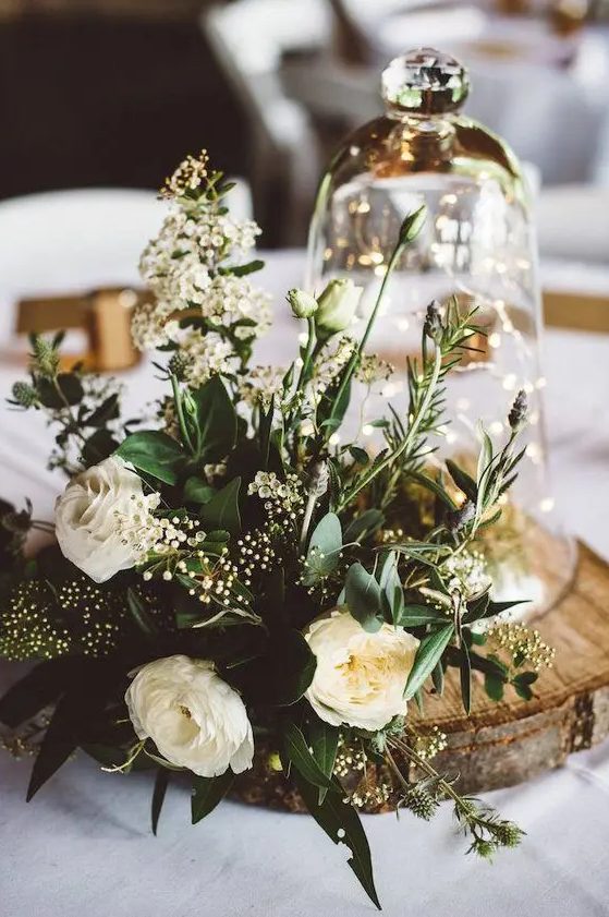 a gorgeous spring centerpiece with neutral blooms, greenery and a cloche with LEDs