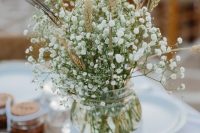 a lovely rustic wedding centerpiece of a jar with baby’s breath and wheat is a simple and cool idea for a fall rustic wedding
