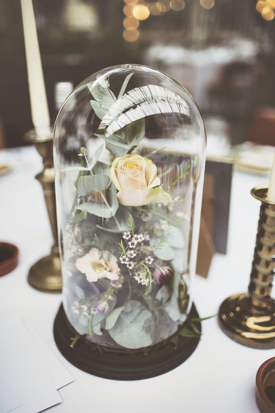 a lovely wedding centerpiece of a cloche with greenery and some neutral blooms is always a good idea