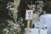 a pretty rustic summer wedding centerpiece of a wood slice, baby’s breath and wheat, a candle holder and a potted succulent