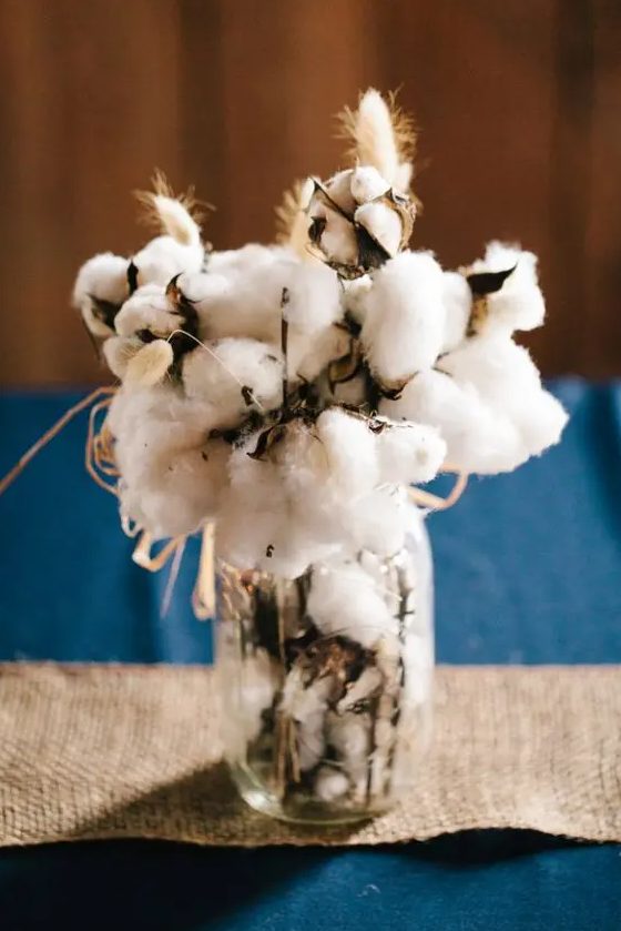 a rustic wedding centerpiece of a jar with cotton and bunny tails is a super soft and cozy idea for a rustic fall or winter wedding