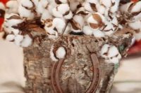 a rustic wedding centerpiece of a tree stump filled with cotton and a horseshoe is a lovely and cozy idea that you can DIY