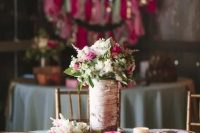 a rustic wedding centerpiece of white and pink blooms with greenery in a vase wrapped with bark
