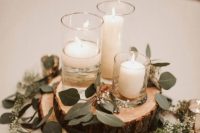 a rustic winter wedding centerpiece of wood slices, greenery and candles in candleholders