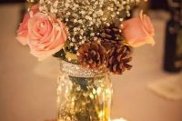 a shiny glam winter wedding centerpiece of white roses, baby’s breath, pinecones, candles and a glitter wood slice is super cool