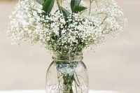 a stack of vintage books and a clear mason jar with a white floral arrangement is a lovely idea for a spring or summer wedding
