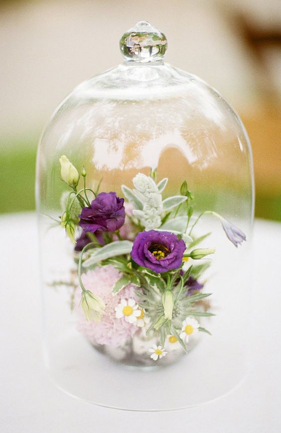 a stylish summer wedding centerpiece of a cloche with purple and white blooms is lovely