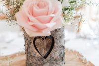 a wood slice with a bark wrapped vase, baby’s breath, greenery and a pink rose is a great barn centerpiece
