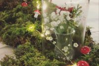 an enchanted forest wedding centerpiece of moss, lights, mushrooms, a cloche with white blooms is a lovely decoration to compose