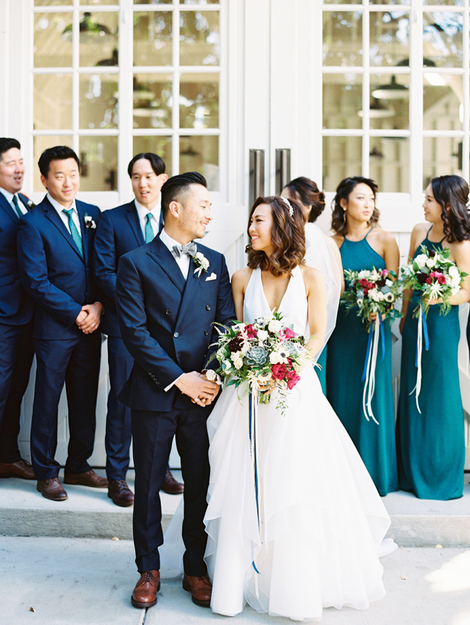 The groom and groomsmen were wearing navy suits, and the bridesmaids were rocking emerald halter neckline maxi dresses