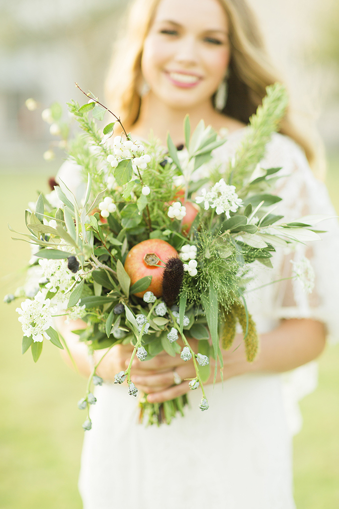 The unusual bouquet made of various greenery, some blooms and a pomegranate