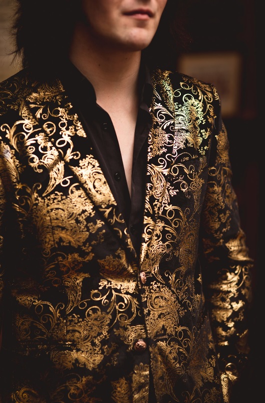 This is one of the groom's looks with a black shirt and a gold patterned jacket