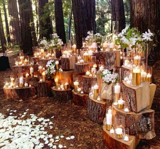 a tree stump altar with candles all over and some blooms