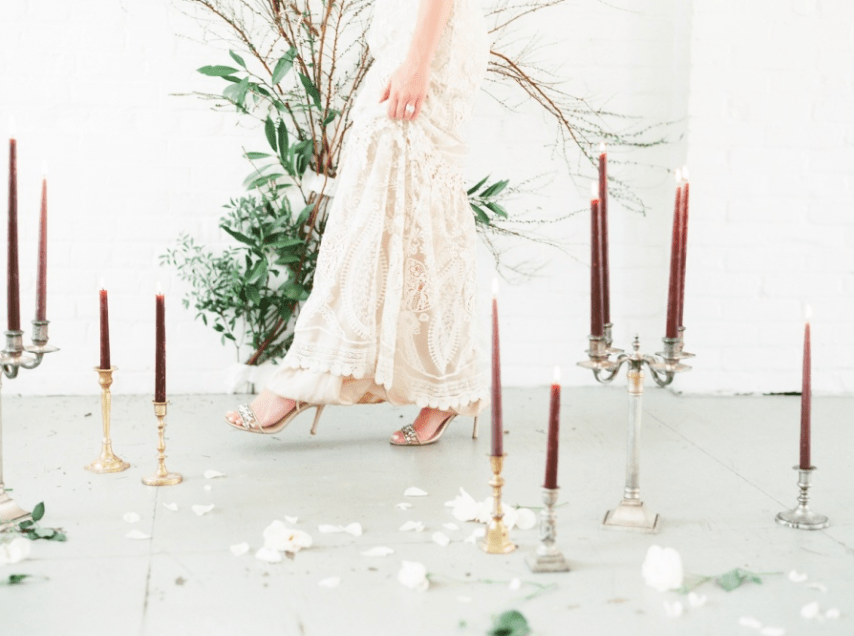 Burgundy candles in refined candle holders and textural greenery helped to create a romantic setting