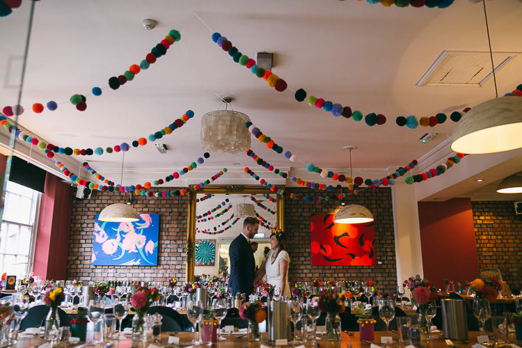 Large pompom garlands hanging over the reception were made by the bride