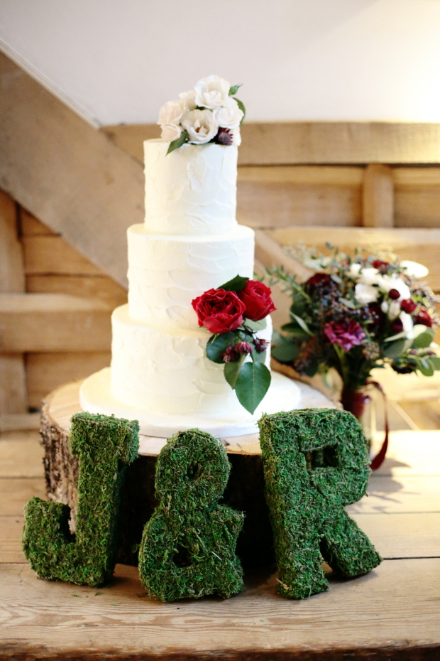 The wedding cake was pure white, with white and red roses and moss monograms