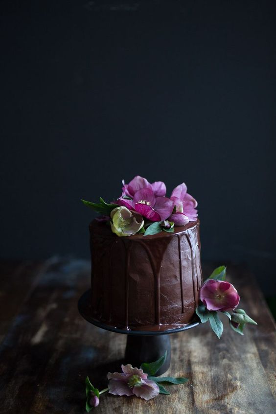 chocolate wedding cake with chocolate drip and pink blooms on top