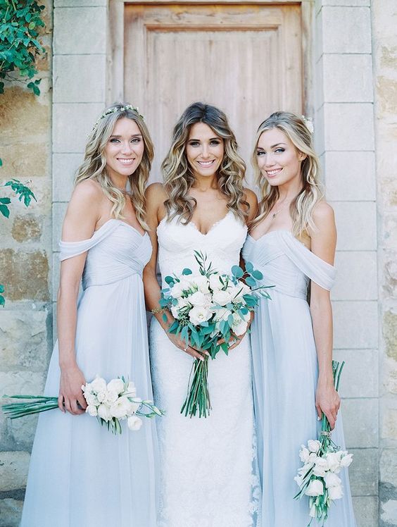 powder blue off the shoulder flowy bridesmaids' dresses and a bride in a spaghetti strap wedding dress with a V neckline