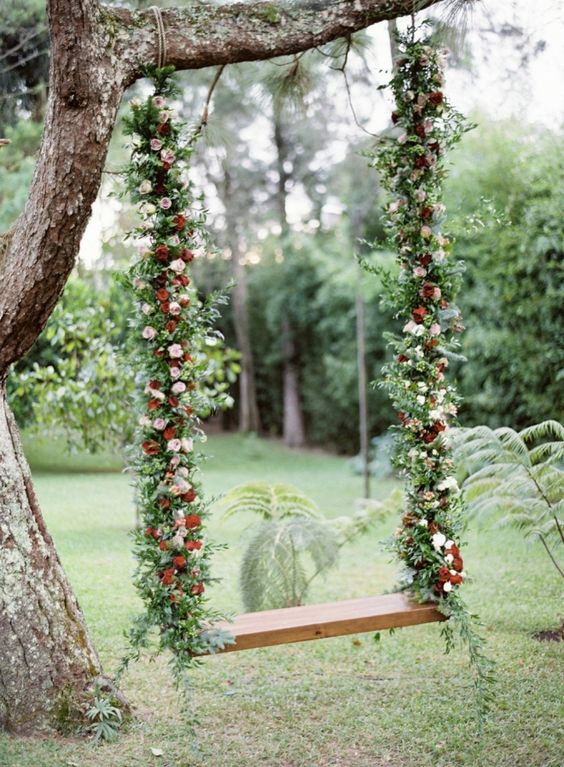fall-inspired swing with greenery and pink and red flowers