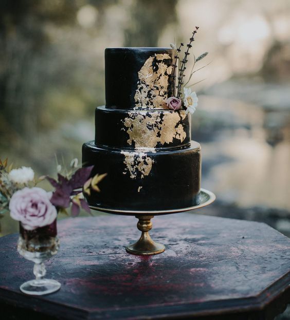 black iced wedding cake with gold detailing and fresh flowers