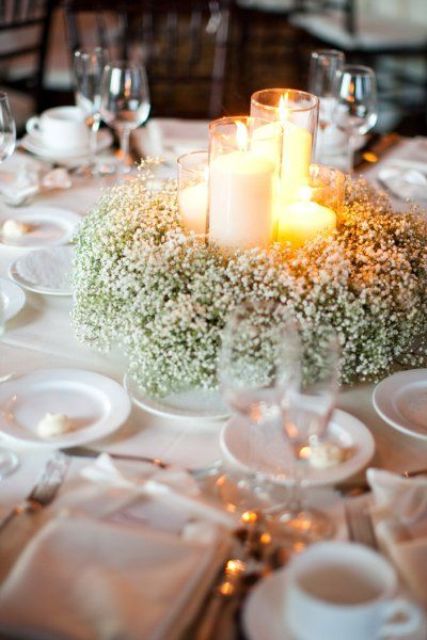 a baby's breath wreath with candles in tall glass candle holders