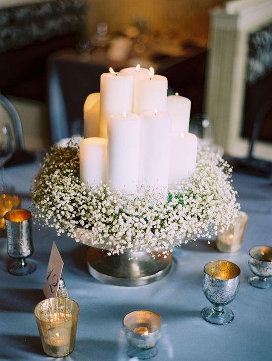 a metallic bowl with baby's breath and lots of pillar candles