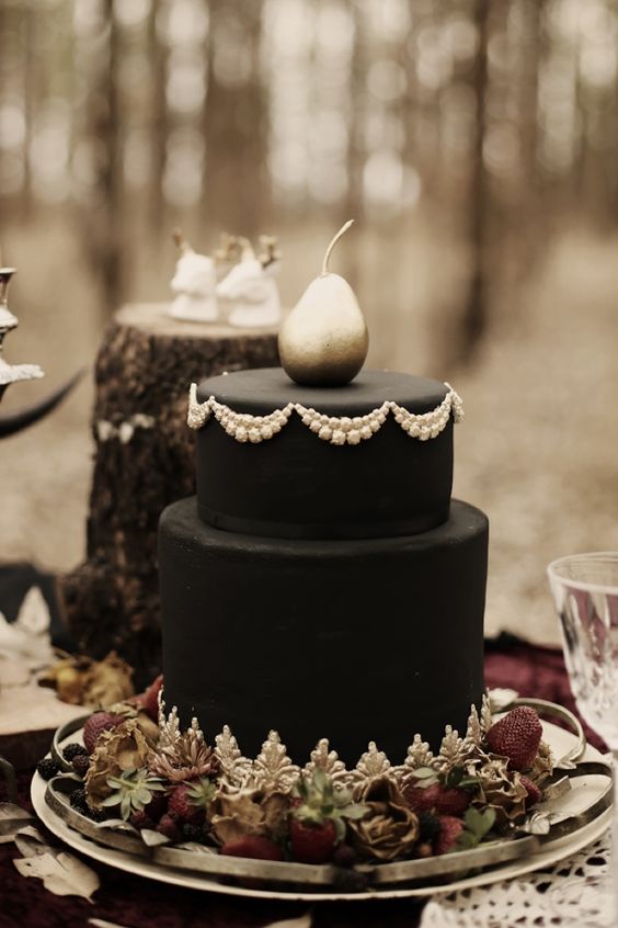 black wedding cake with white cream decor and a silvered pea ron top