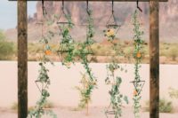 25 geometric desert wedding arbor with hanging greenery and color-coordinated flowers scattered throughout