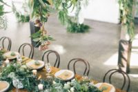 26 greenery and white blooms on the table match the hanging decor above it