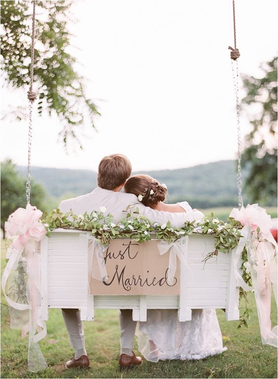 a swinging bench decorated with greenery and blush fabric bows