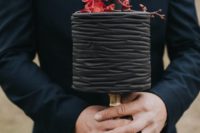 31 textural black wedding cake topped with red flowers