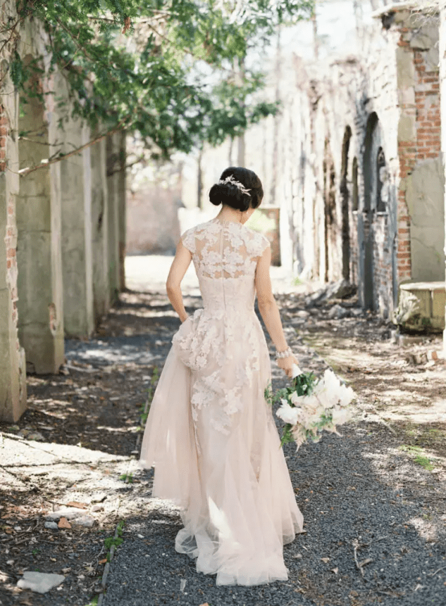 a blush wedding dress with cap sleeves, lace appliques and an illusion neckline