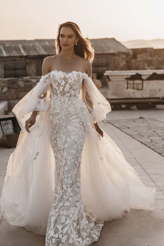 a dramatic off the shoulder wedding dress with floral applique, bell sleeves, an overskirt with a train is amazing