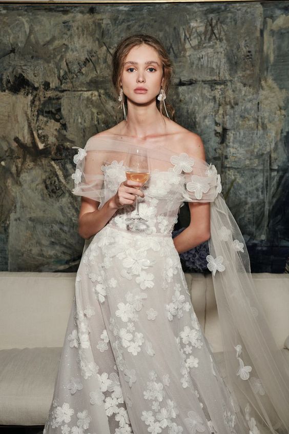 a dreamy off the shoulder wedding dress with floral appliques and a catchy shoulder cover with a train