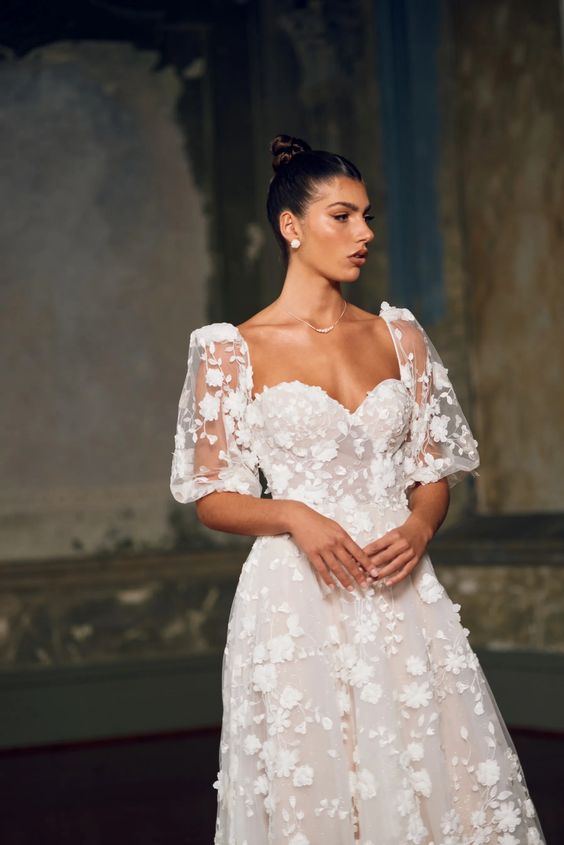 a feminine wedding dress with floral applique all over and short puff sleeves plus a sweetheart neckline