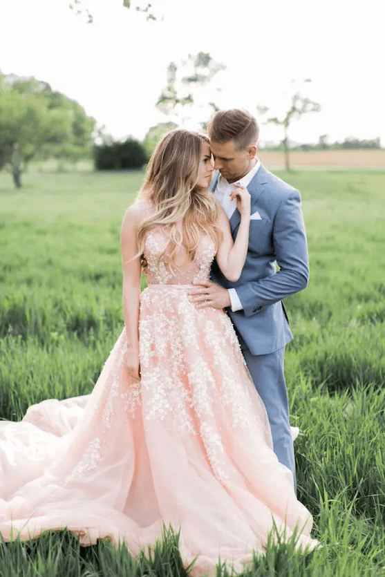 a pink sleeveless wedding dress with a plunging neckline and pearl floral applique all over the gown