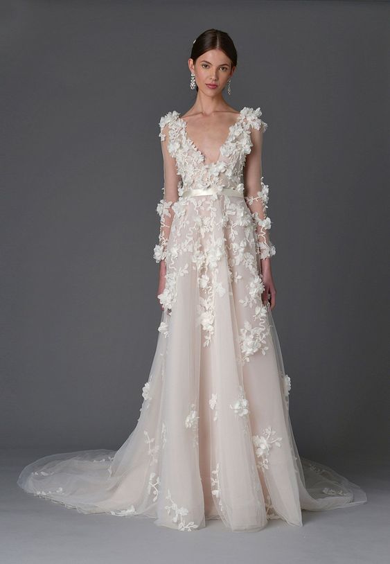 A romantic A line blush wedding dress with a V neckline, floral applique, a train for a formal and refined wedding