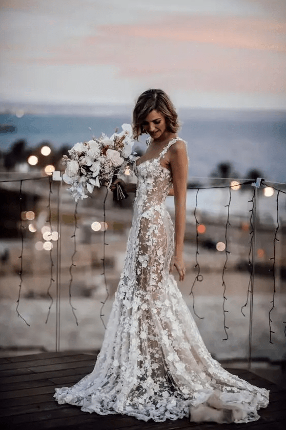 A sexy semi sheer mermaid wedding dress with floral appliques all over the dress, a train and thick straps plus a deep neckline
