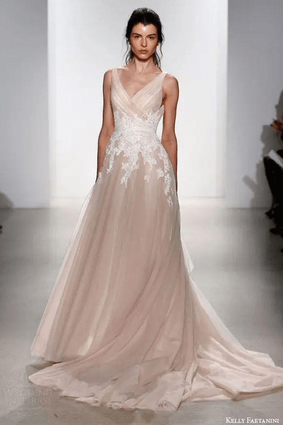 a sleeveless blush wedding dress with white lace appliques on the waist line and a train